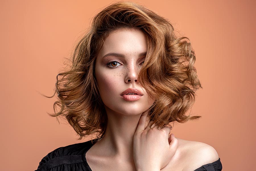 Beautiful brown haired with stylish short hairstyle. Woman with a curly hair. Beautiful young woman with freckles on face. Closeup portrait of an attractive girl with a brown makeup.
